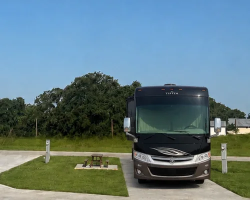 A motorhome parked on a full-hookup concrete site with its own picnic table at Twin Oaks Resort